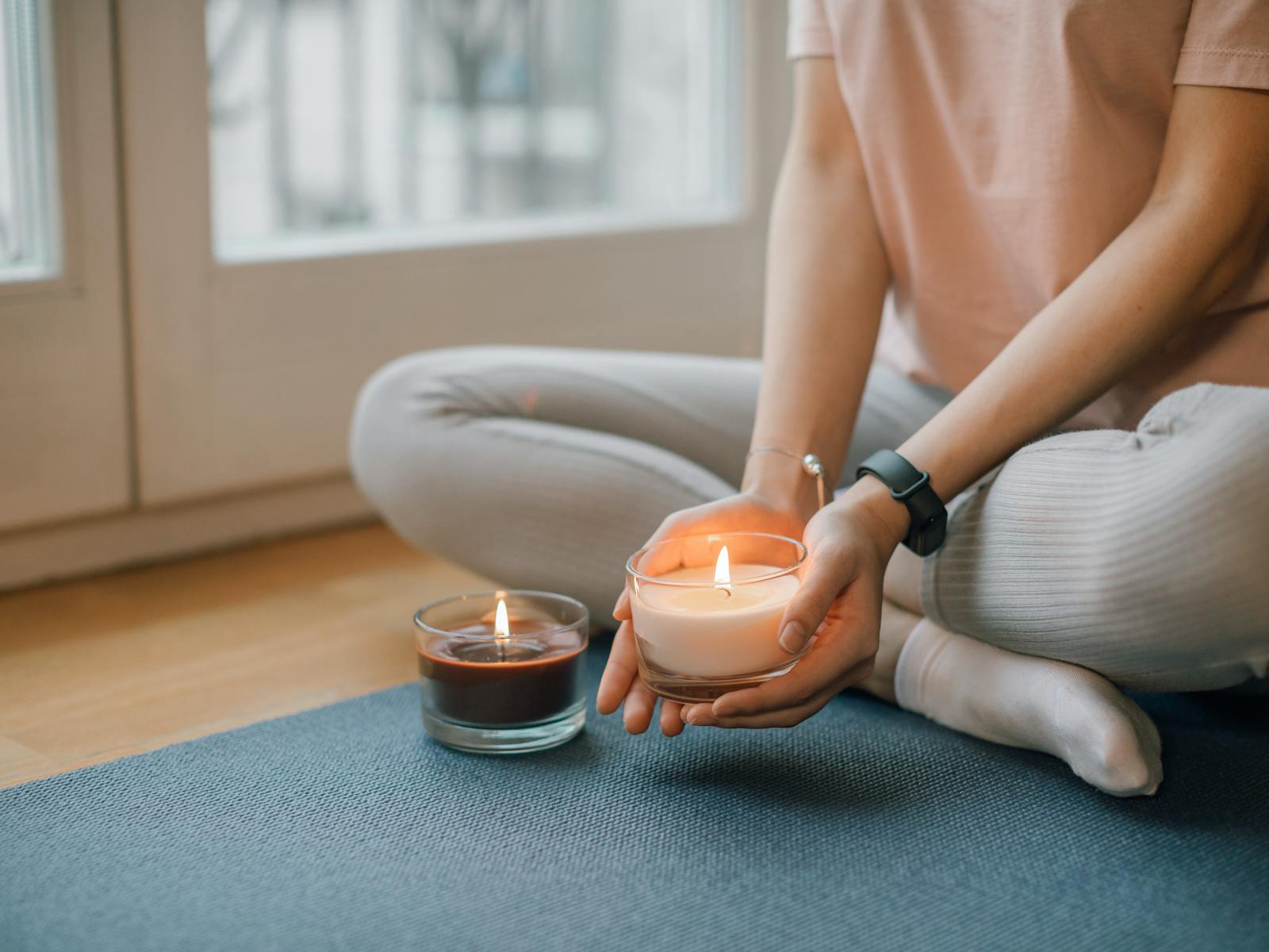 Hands holding a candle, mat on the floor — Restore class
